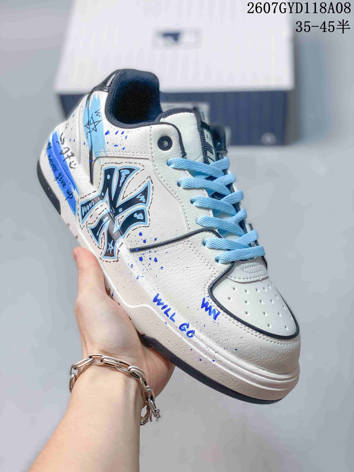 Angled side view of the white sneaker showing blue graphic artwork, light-blue laces, splatter details and layered sole construction.