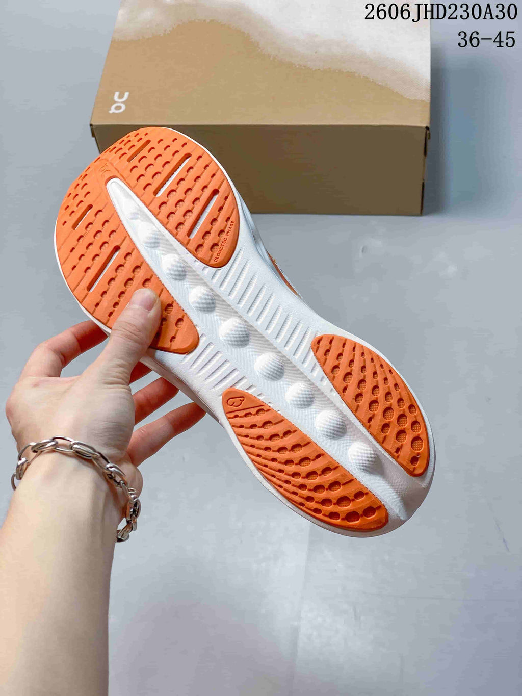 Underside of a white and orange sneaker showing the patterned outsole