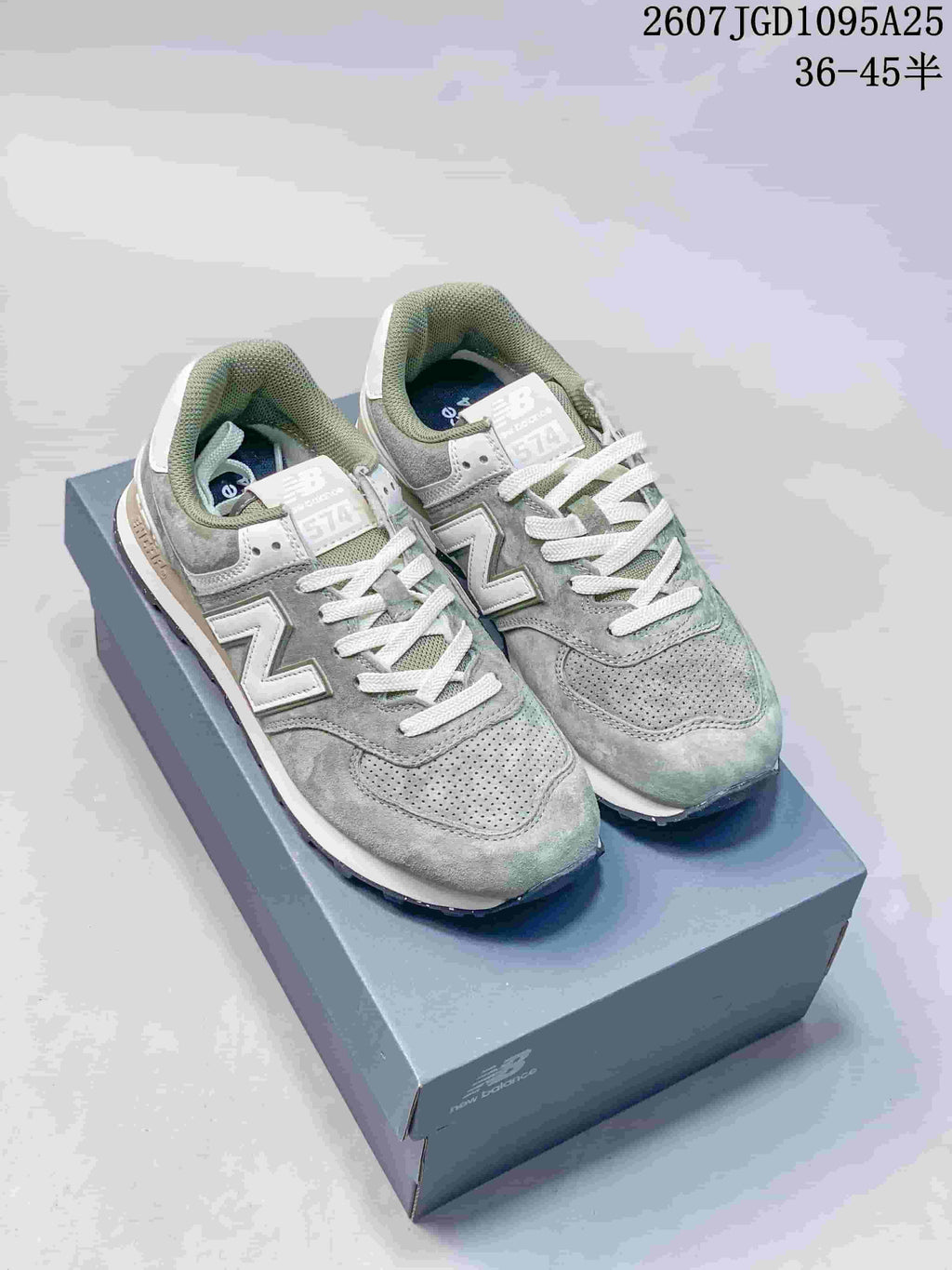 Pair of green and white New Balance 574 sneakers displayed on a shoebox.