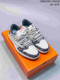 Pair of white and dark patterned low-top sneakers with cream laces, shown on an orange box