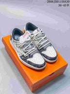 Pair of white and dark patterned low-top sneakers with cream laces, shown on an orange box