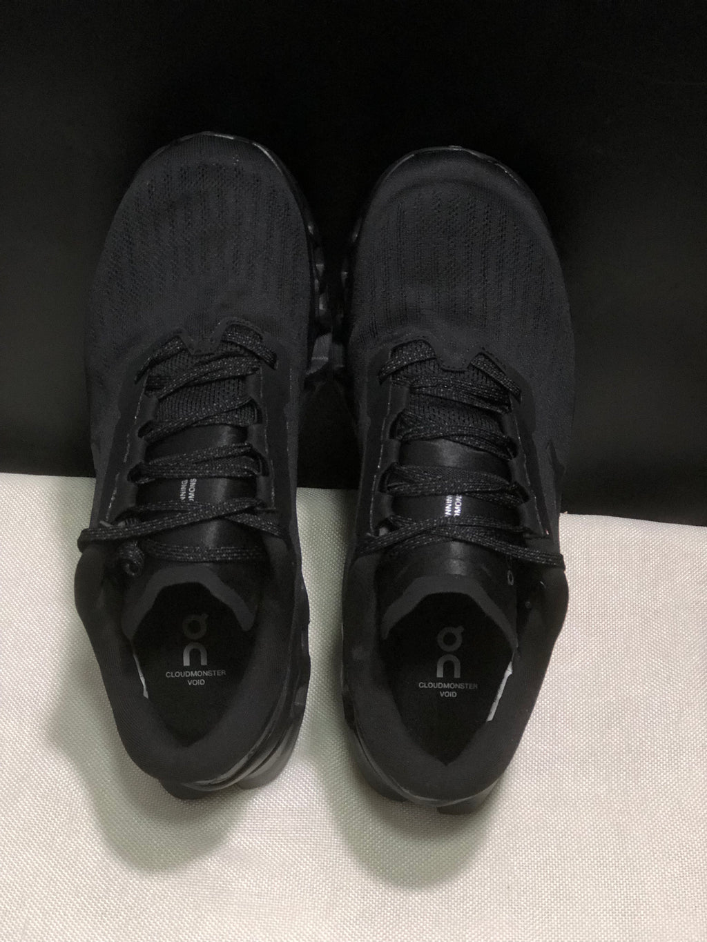 Top-down view showing the black textured uppers, laces and branded insoles.