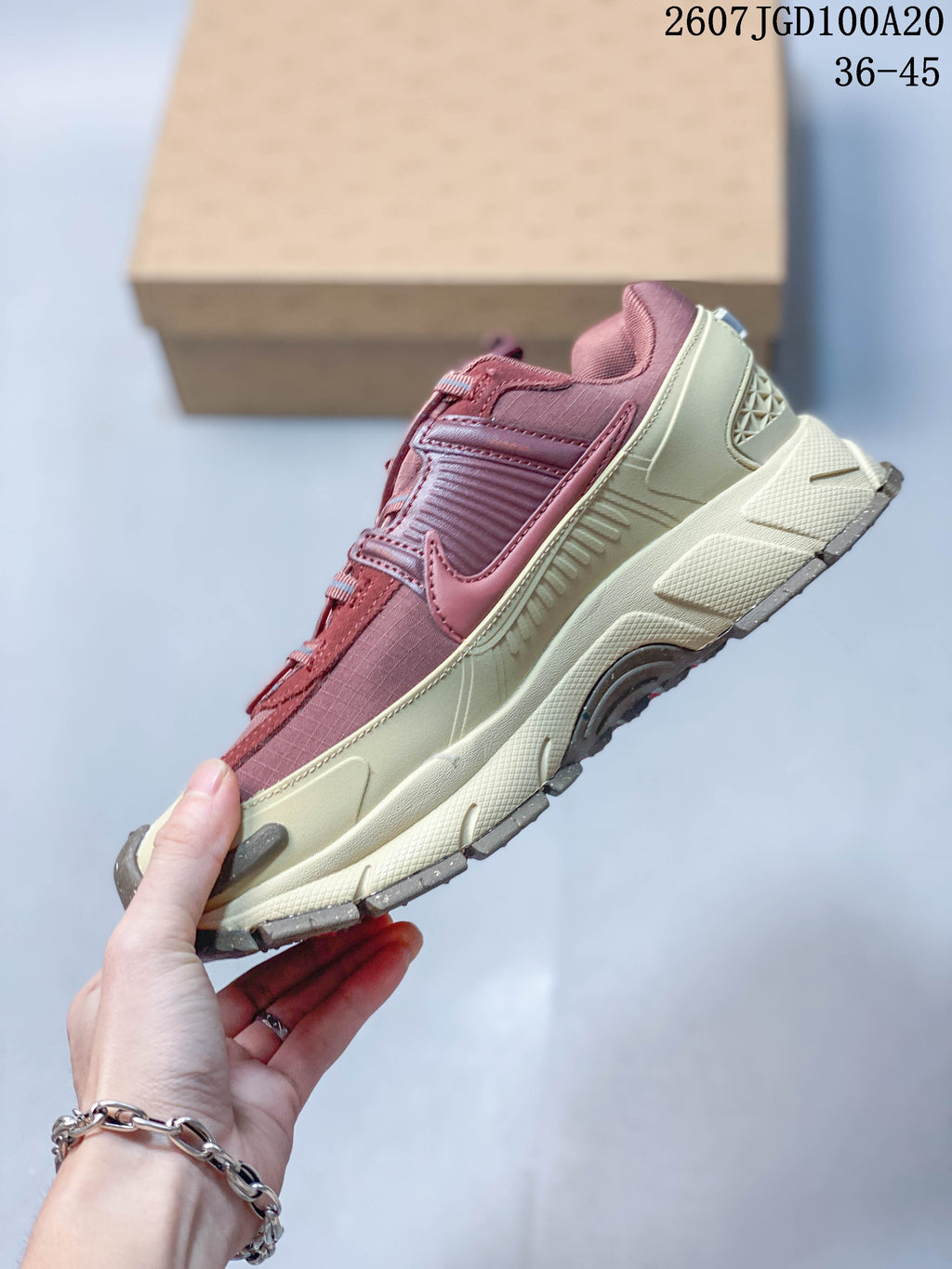 Side profile highlighting the layered burgundy upper, cream midsole, and gray outsole accents.