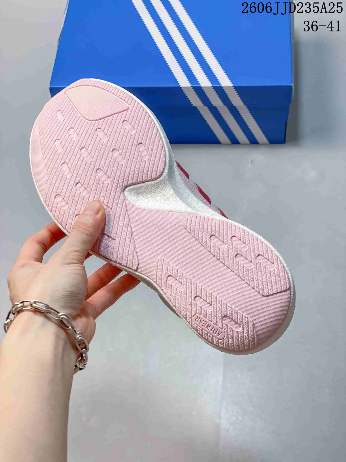Bottom view of a pink sneaker showing the textured outsole and herringbone-style tread pattern.