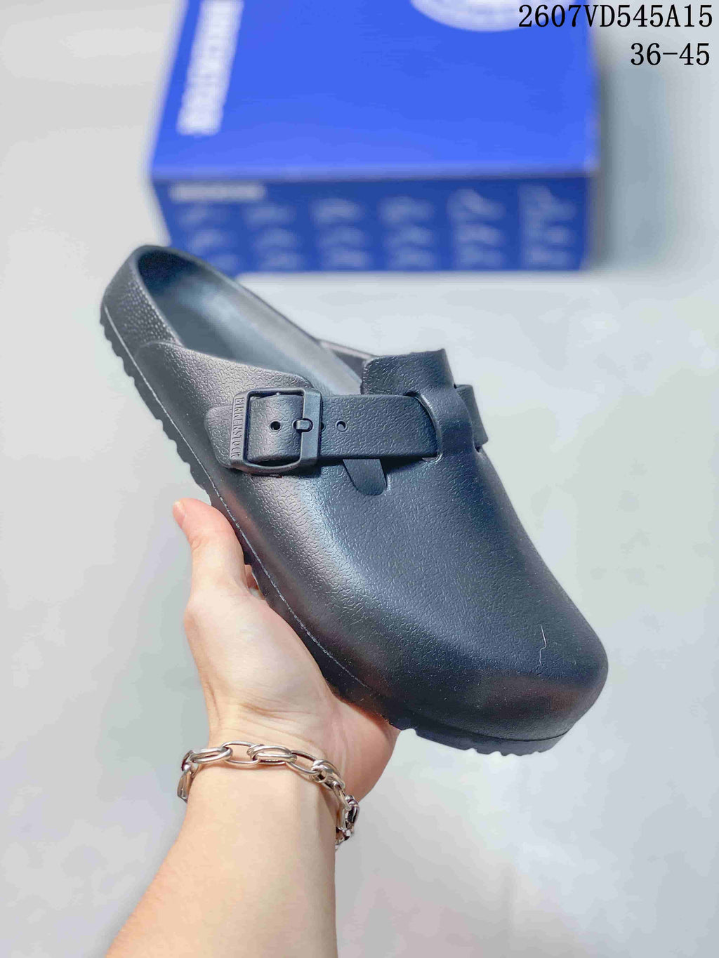 Angled view of the black sandal showing the buckle fastening, closed toe and textured outsole.