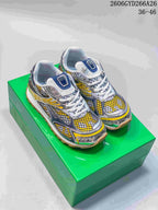Pair of yellow, blue, silver-tone and white Bottega Veneta Orbit low-top sneakers on a green box