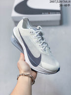 Angled side view of a white and light gray Nike running shoe with a dark navy Swoosh, textured upper, and ZoomX midsole branding.