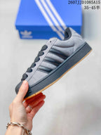 Side view showing the grey upper, black side stripes, black midsole and gum outsole.