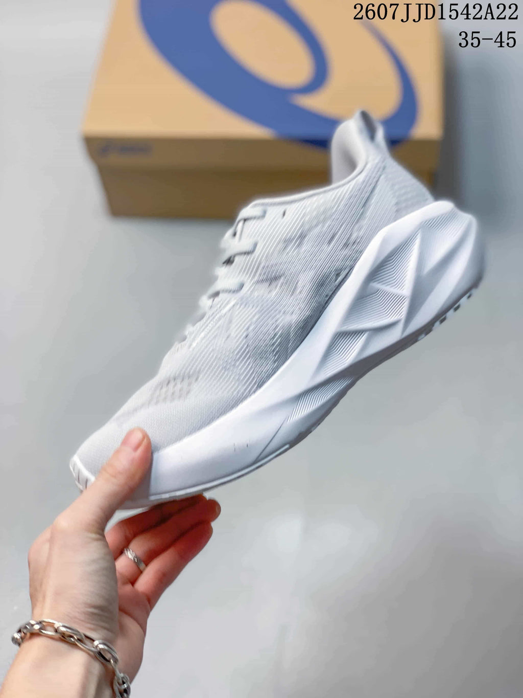 Side profile of the light-colored running shoe showing the textured upper, lace area, sculpted midsole, and outsole design.