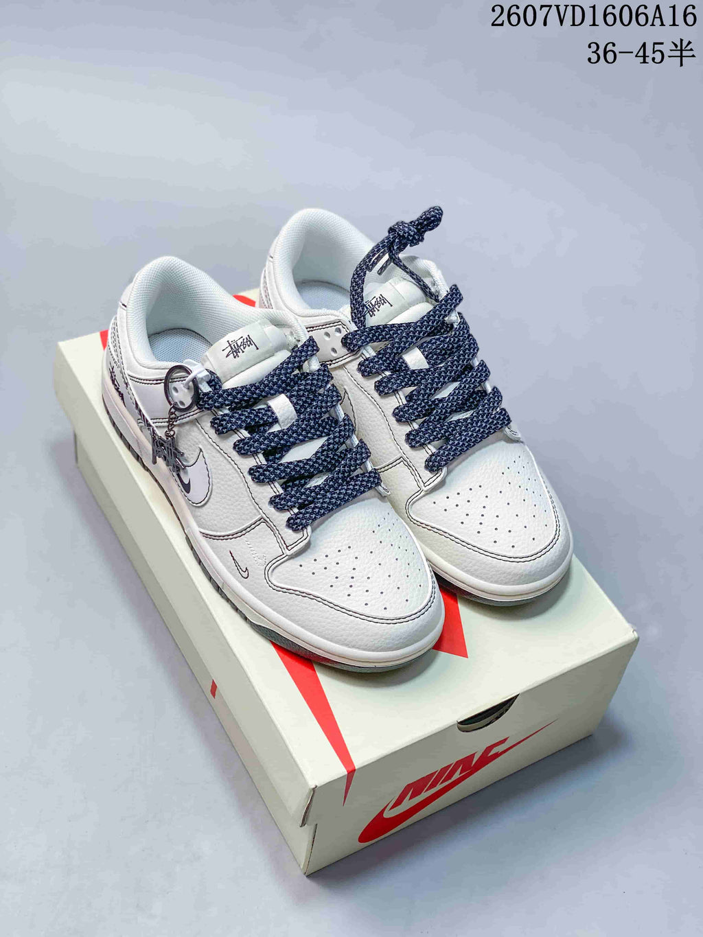 Pair of white low-top Nike SB Dunk-style sneakers with dark navy rope laces and patterned side details displayed on a Nike shoe box.