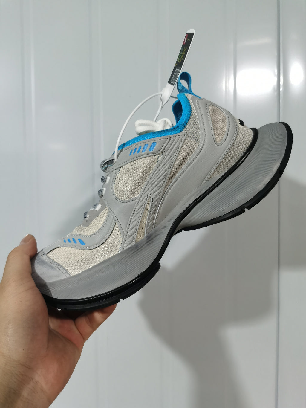 Side and top view showing the grey and blue sneaker upper, blue collar trim, white laces, and sculpted grey midsole.