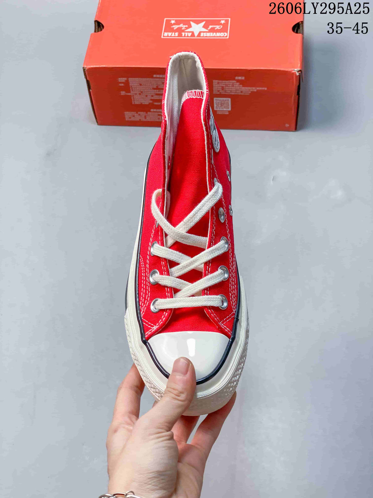Top view of a red Converse high-top sneaker showing white laces, silver eyelets, white toe cap, and contrast trim.