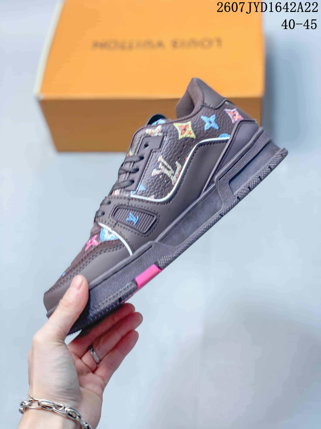 Side view of the dark brown low-top sneaker with multicolor motifs, layered panels, lace closure, and pink outsole accent; image text shows 2607 TYD1642A22 and 40–45.