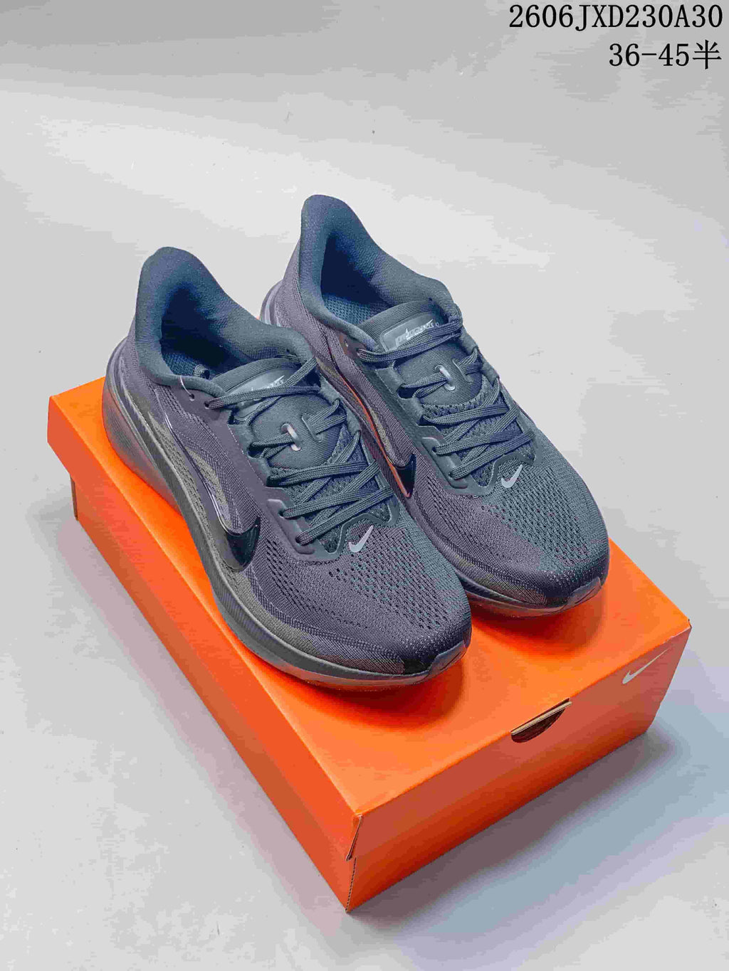 Pair of dark gray Nike Air Zoom Pegasus 42 running shoes displayed on an orange shoe box.
