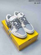Pair of white, grey, charcoal and yellow low-top sneakers on a yellow box