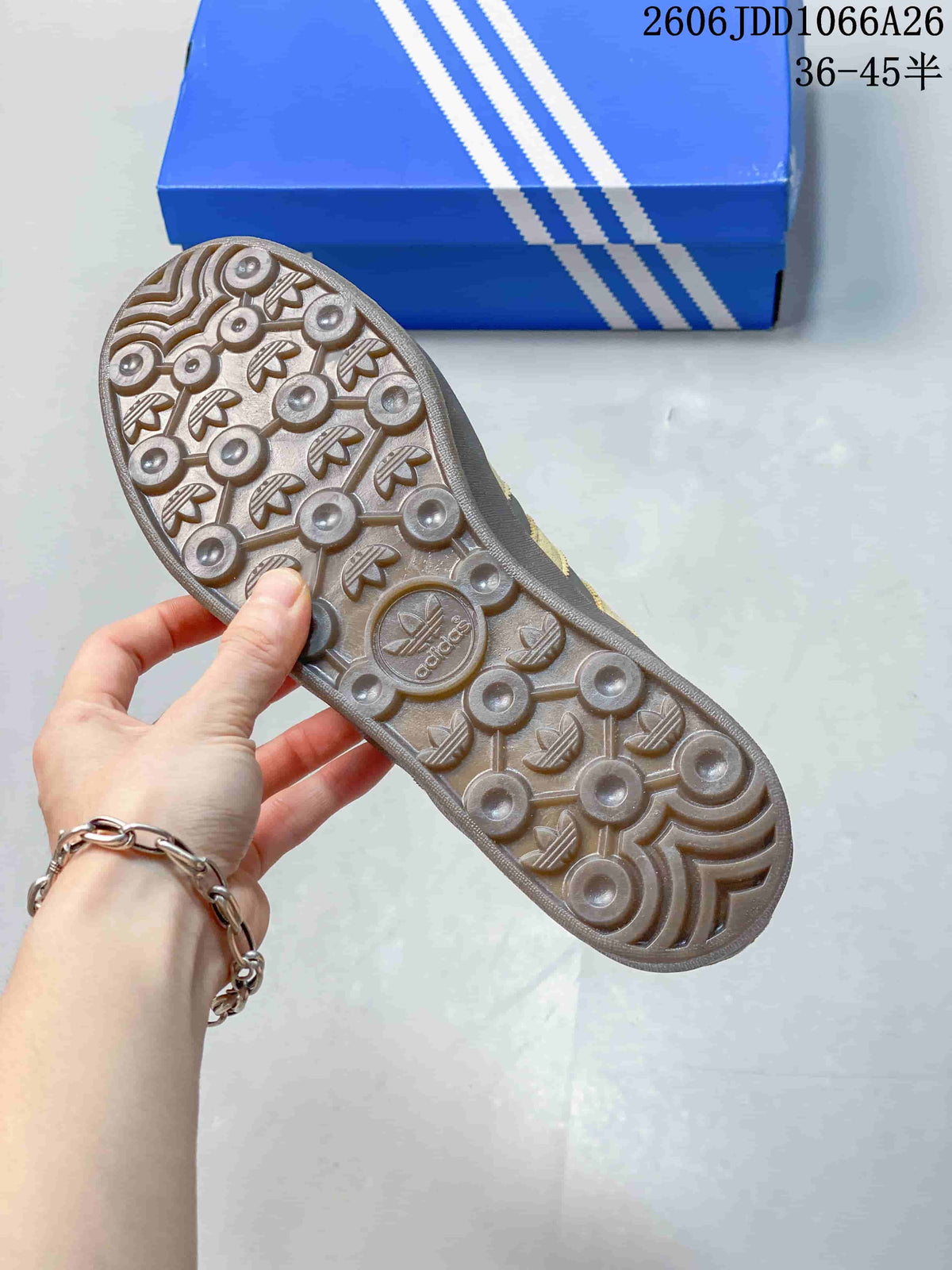 Close view of the textured outsole showing circular tread elements and repeated trefoil motifs.
