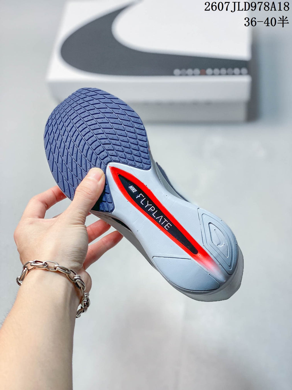 Bottom view of a Nike running shoe showing a dark blue patterned outsole and visible Flyplate branding.