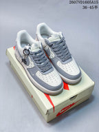 Pair of white and gray low-top sneakers with gray laces, patterned side panels, white toe boxes, and gray contrasting details.