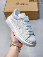 Side view of a white textured platform sneaker with a pale blue heel panel and wide laces.