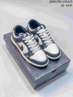 Pair of white and navy low-top sneakers with dark patterned laces, shown on a box.