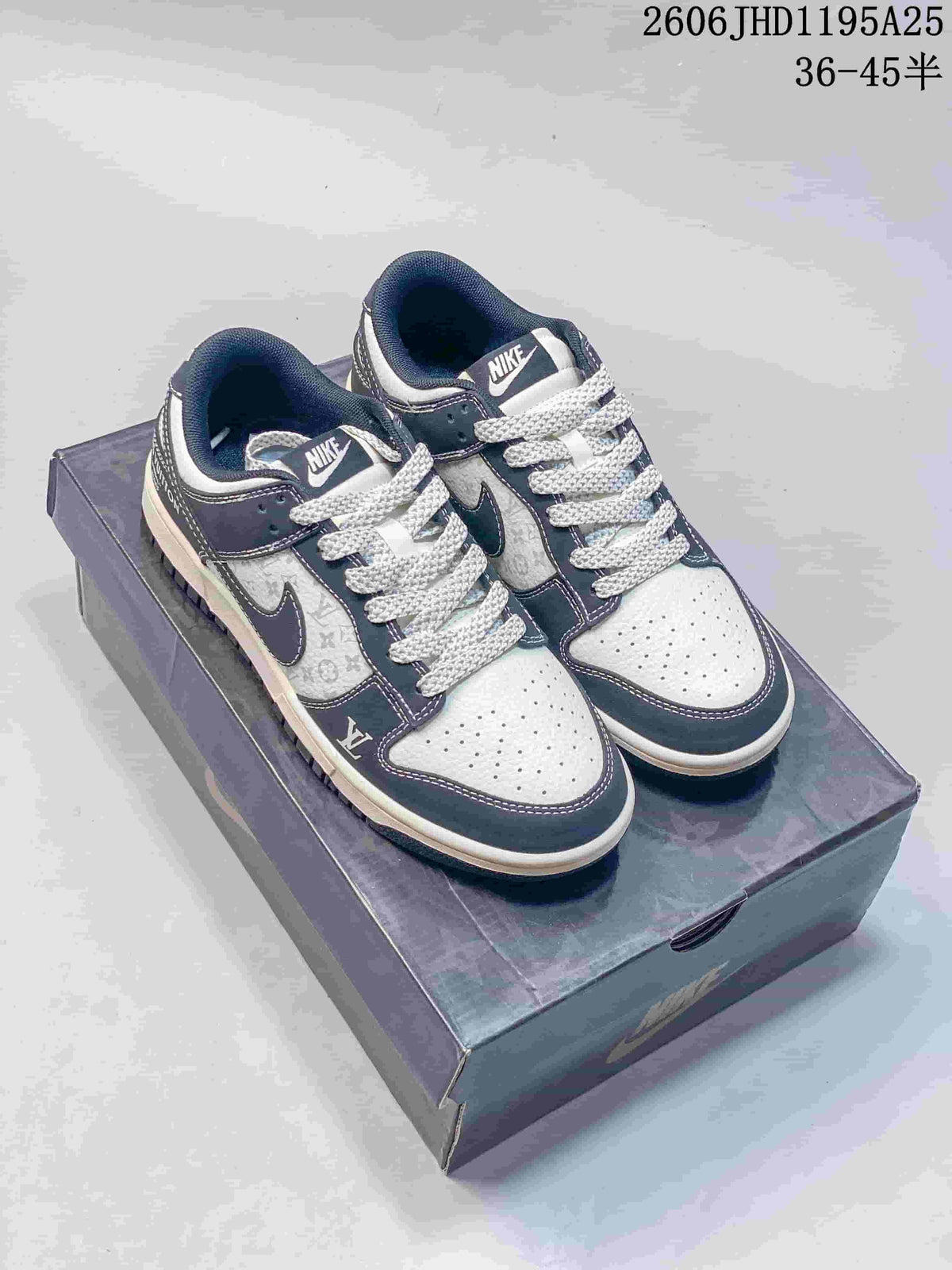 Pair of white and navy low-top sneakers with dark patterned laces, shown on a box.