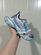 Angled view of the sneaker showing the layered side construction, lace-up front, padded collar and contrasting blue outsole.