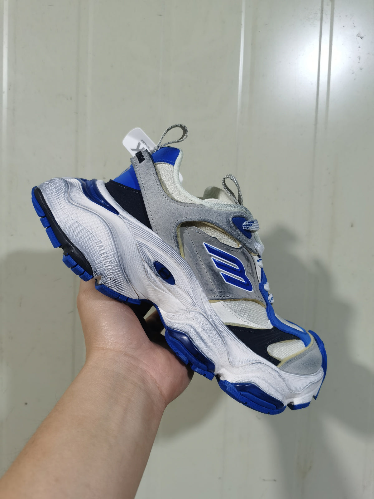 Close angled view of the sneaker showing the side panels, logo, pull tabs, and chunky textured sole.