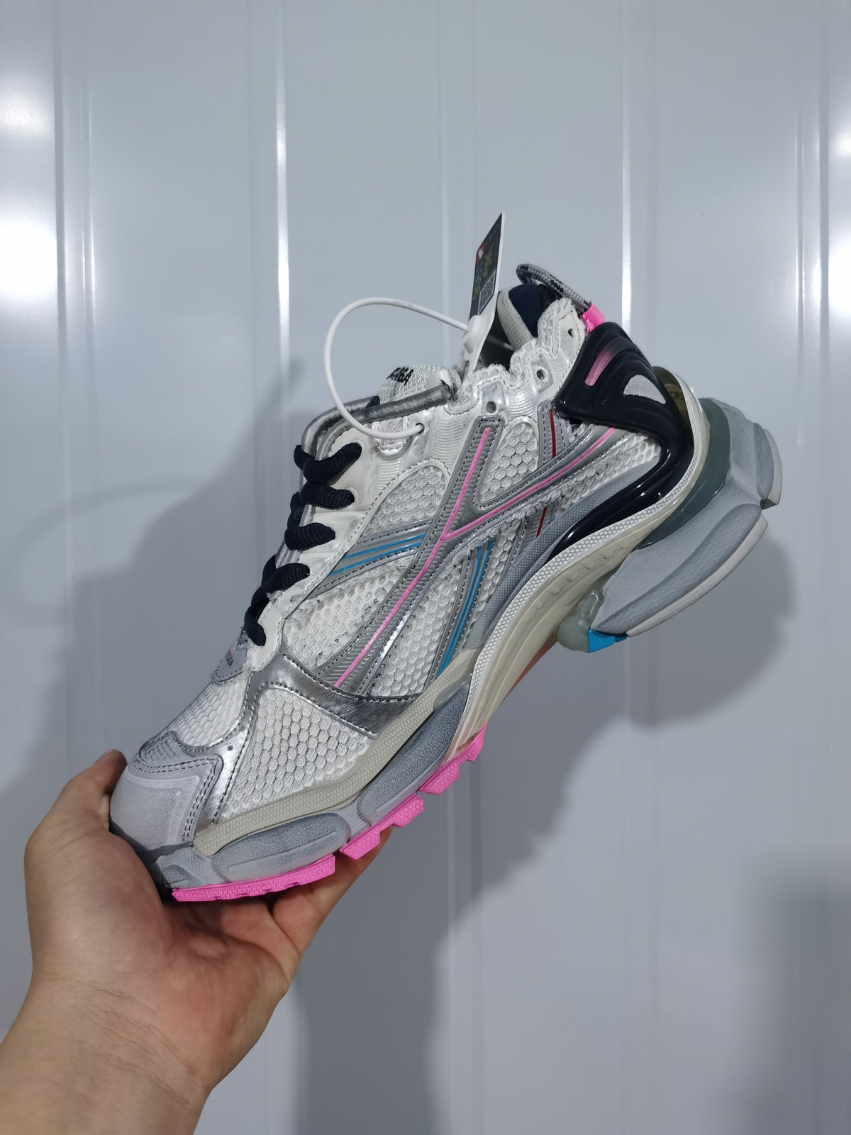 Angled view of the Balenciaga Runner sneaker showing the layered upper, black laces, silver details and pink outsole accents.