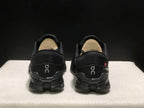 Rear view of the black On Cloud X4 pair showing the heel branding and outsole structure.