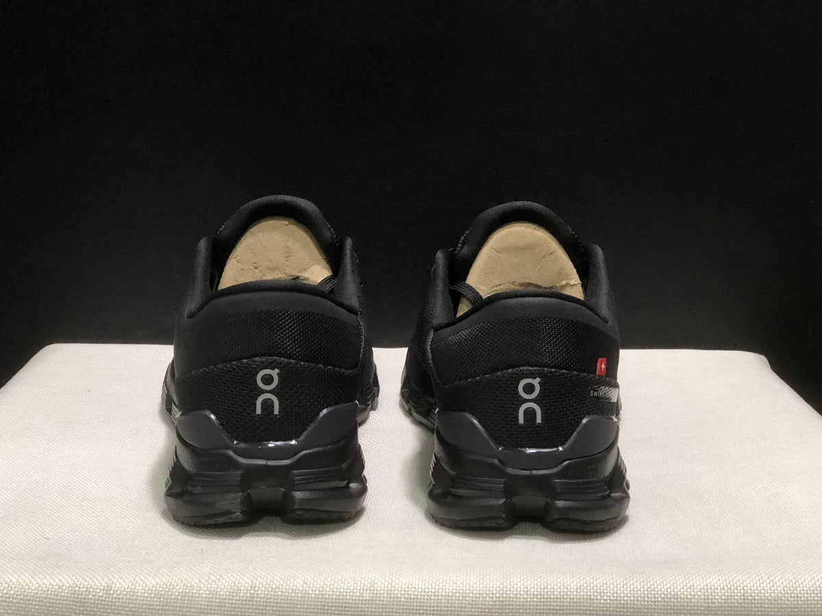 Rear view of the black On Cloud X4 pair showing the heel branding and outsole structure.