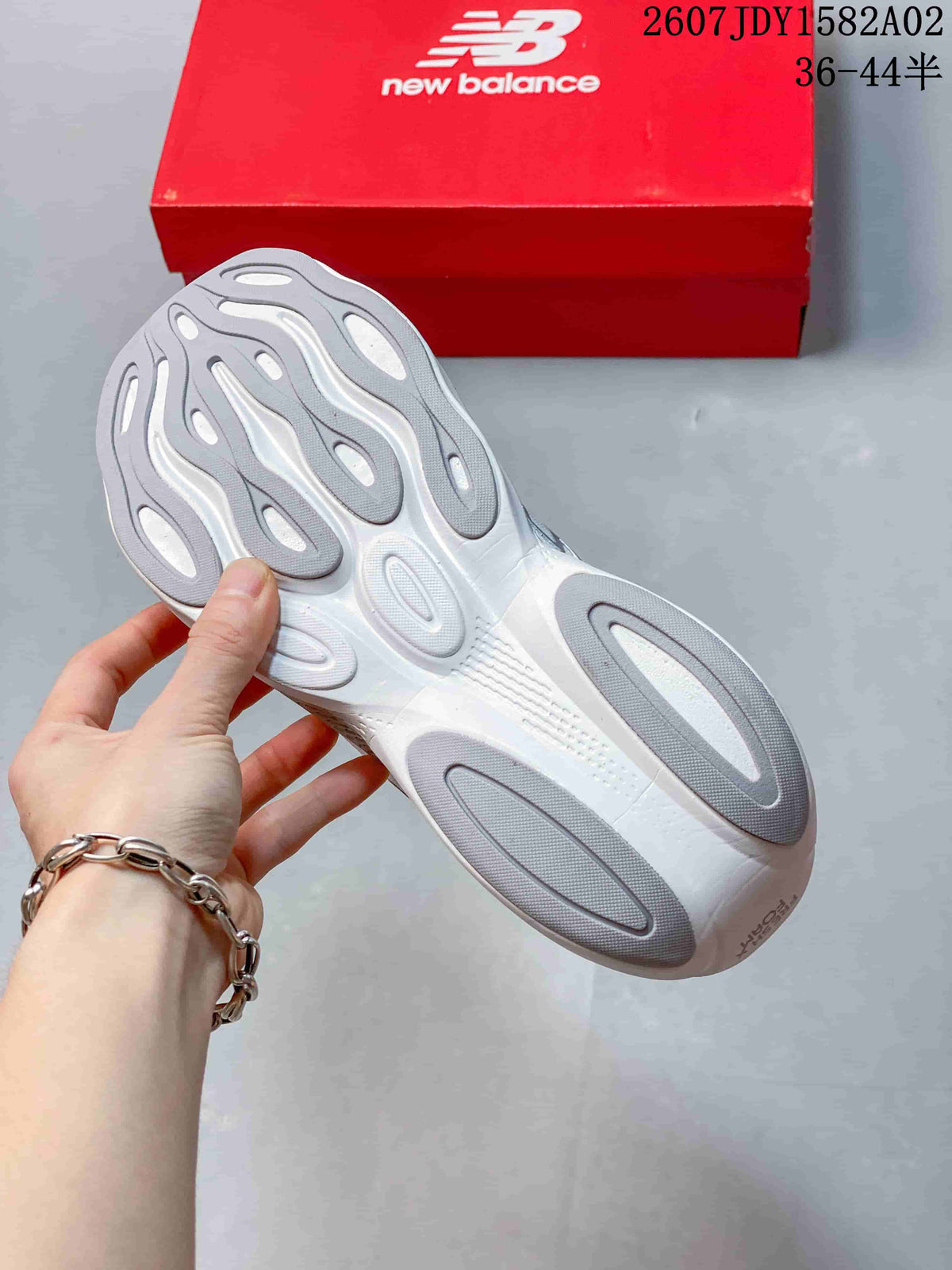 Underside view of a white running shoe with a sculpted grey-and-white outsole.
