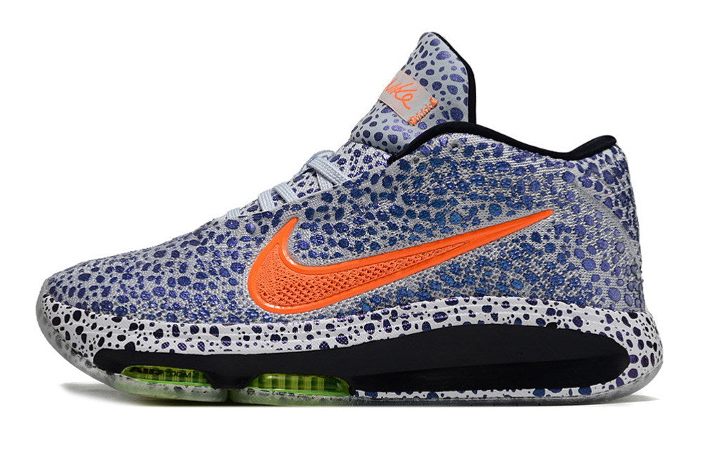 Side profile of a patterned blue and white Nike GT Hustle 3 with orange detailing.