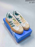 Pair of white and green Adidas Gazelle Bold sneakers displayed on a blue Adidas shoe box, showing the layered gum-colored platform sole.
