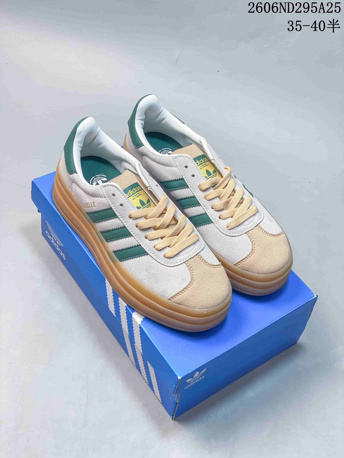 Pair of white and green Adidas Gazelle Bold sneakers displayed on a blue Adidas shoe box, showing the layered gum-colored platform sole.