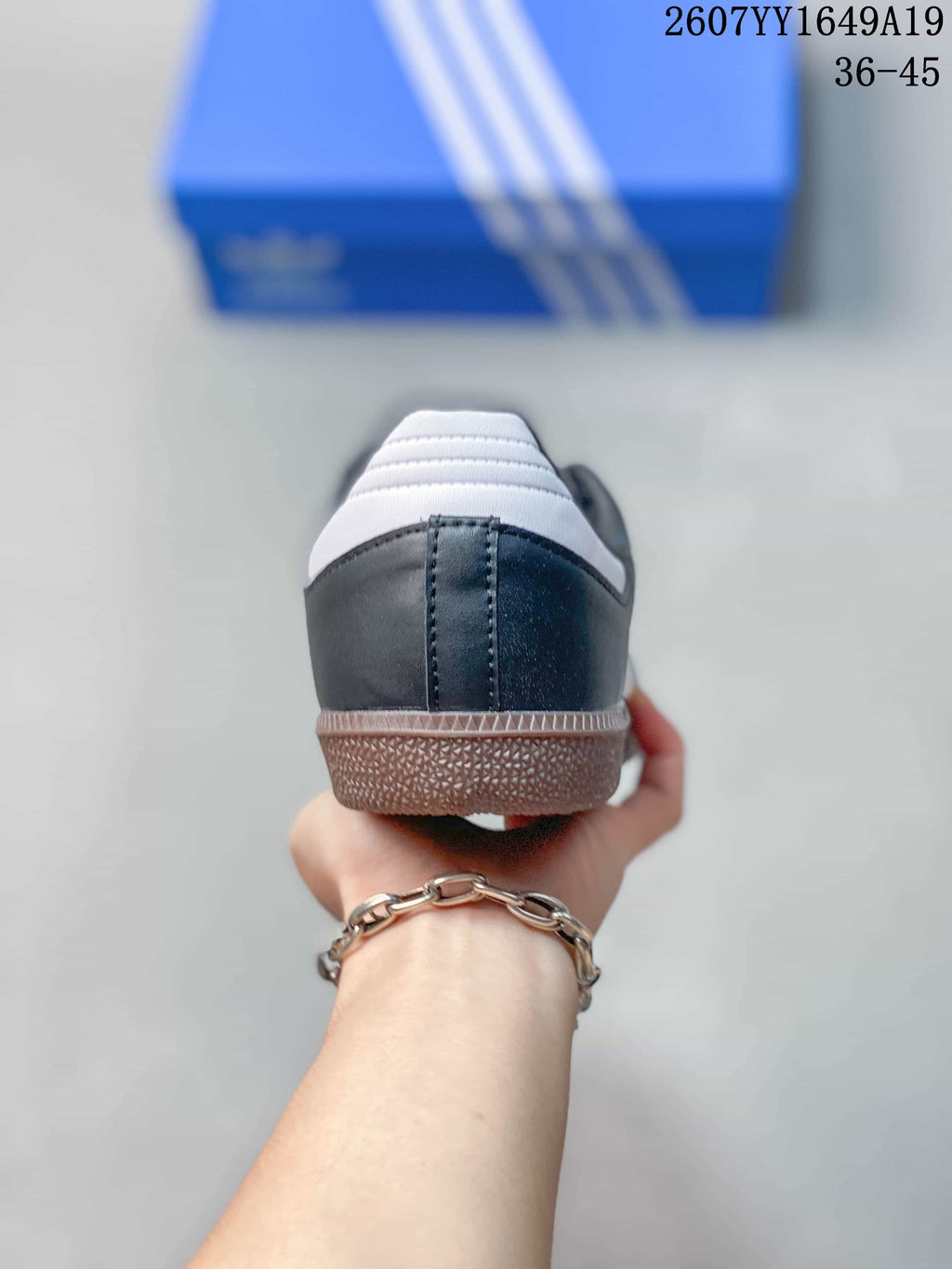 Rear view of the black sneaker showing the white heel tab, stitched heel panel and textured gum-colored sole.