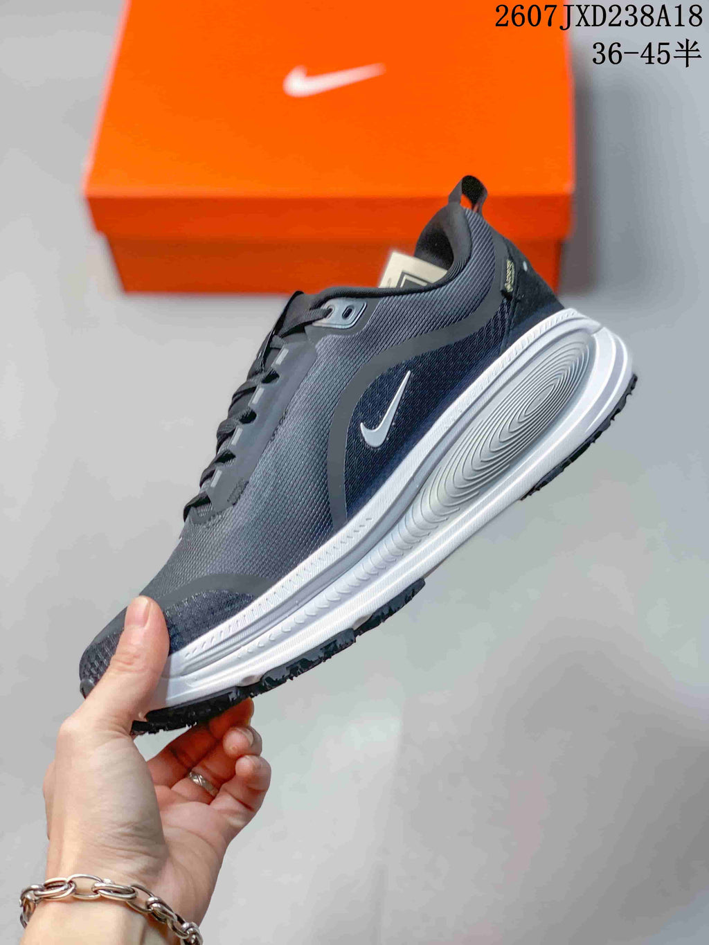 Side profile of the dark gray and white running shoe showing the Swoosh logo, layered midsole, and textured upper.