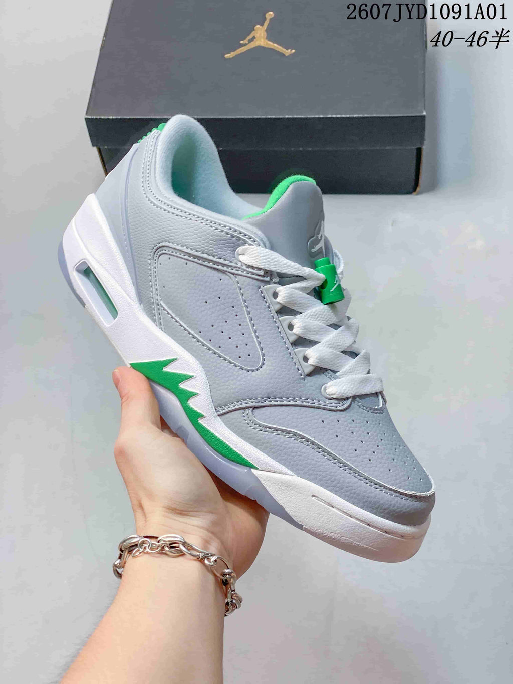 Close-up side view of a gray sneaker with green accents, perforated panels, and white laces.
