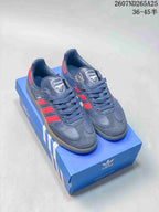 Navy blue and red adidas Samba sneakers displayed on a blue adidas shoebox.