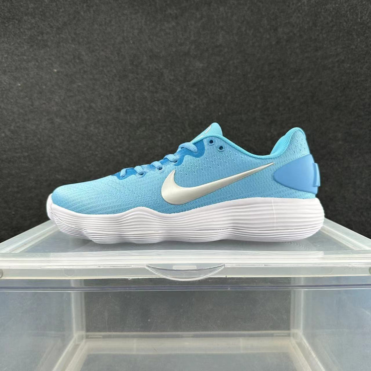 Side view of a blue low-top Nike sneaker with a white side logo and ridged white sole