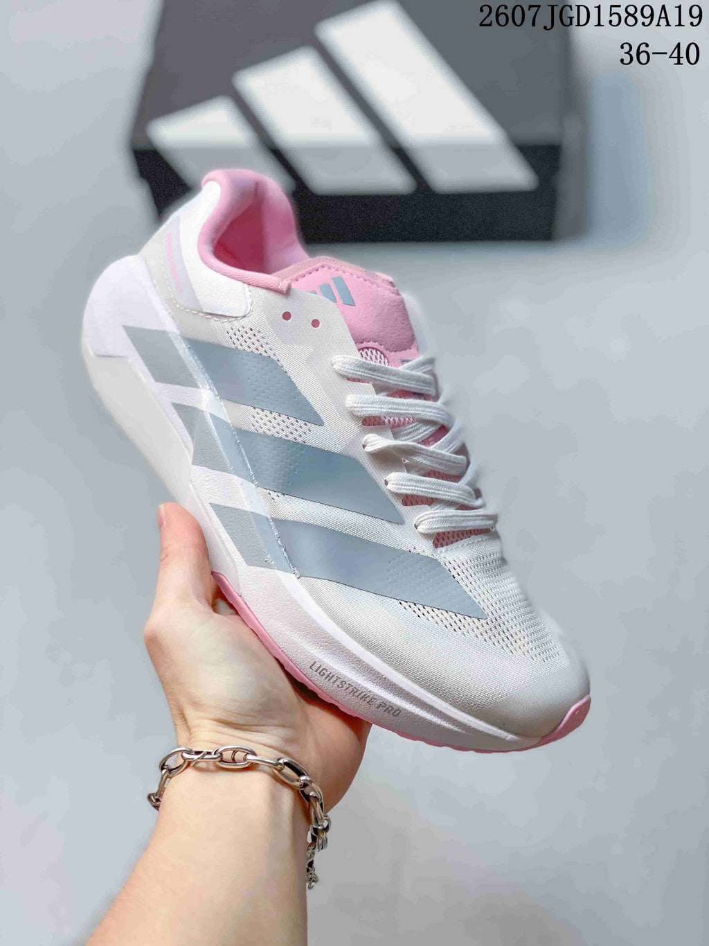 Angled side view of the white adidas trainer showing gray side stripes, pink collar details and the outsole edge.