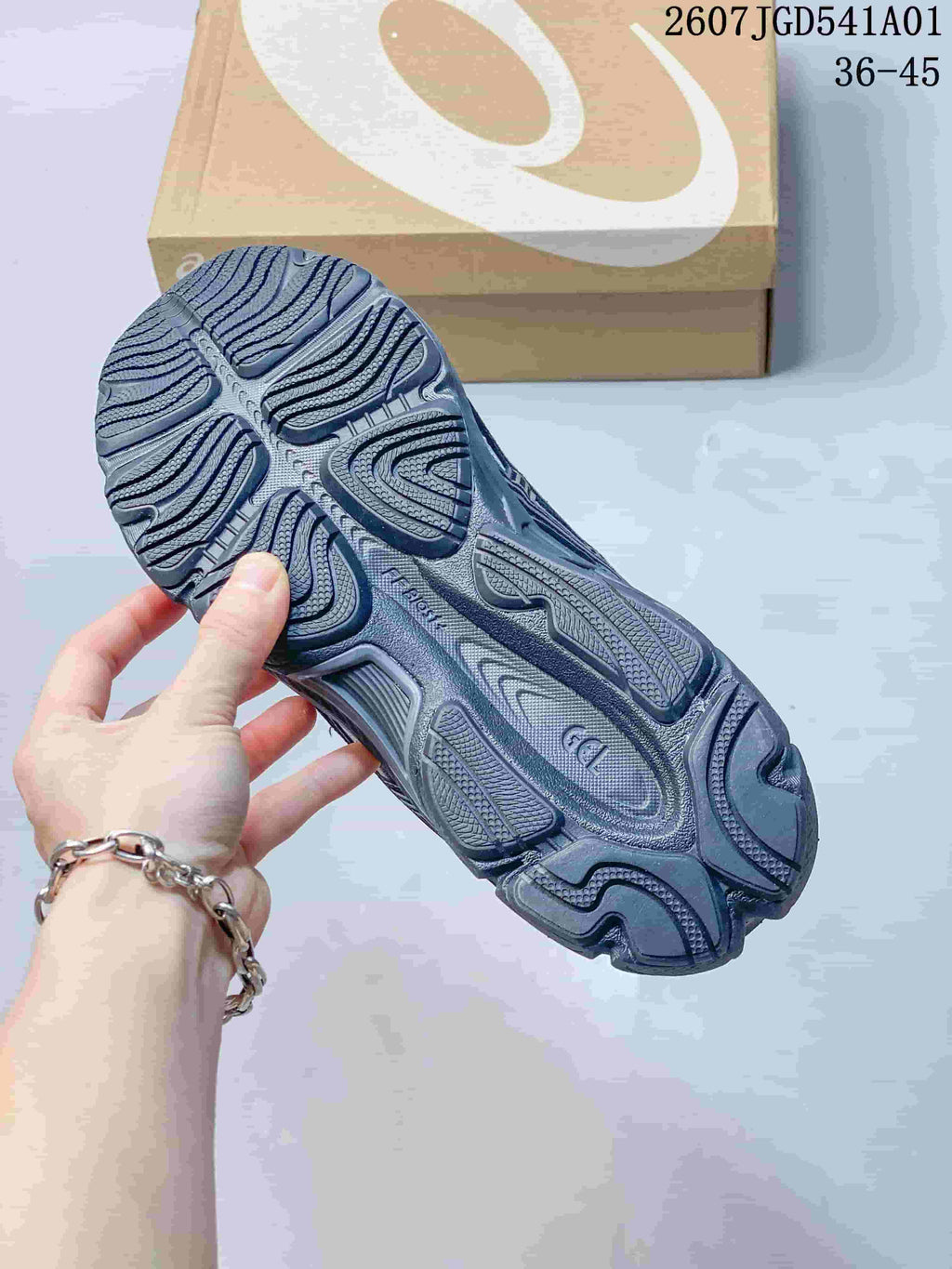 Close-up of the patterned outsole on a navy and silver sneaker