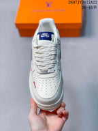 Top view of the sneaker showing white laces, perforated toe box, tongue label, and metallic lace ornament.