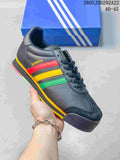 Dark Adidas Samoa sneaker with yellow, red and green side stripes, photographed in front of a blue shoebox.