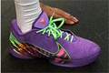 Purple Nike LeBron 22 shoe with bright green laces and a multicolor side and heel graphic.