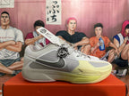 Side profile of a gray and pale yellow Nike basketball shoe with Swoosh detailing.