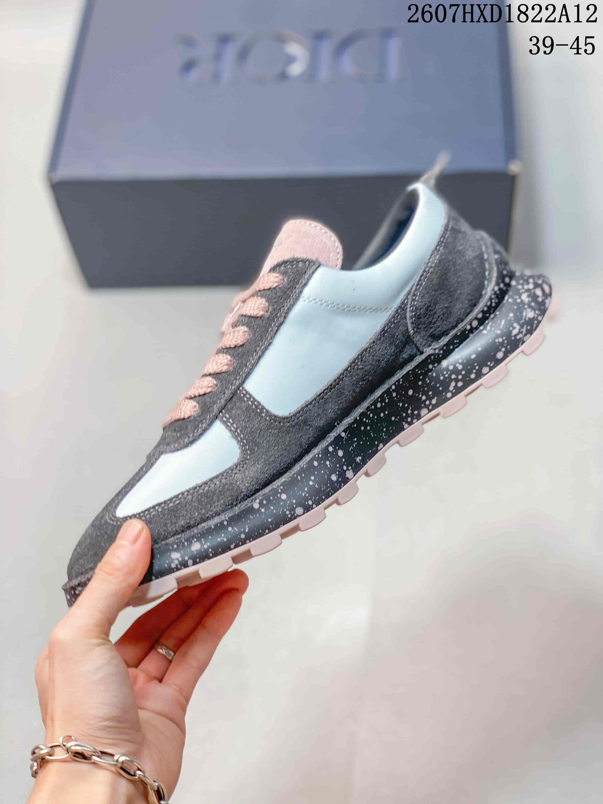 Side profile of the sneaker showing the layered gray and white upper, Dior side detail, speckled midsole, and lugged outsole.