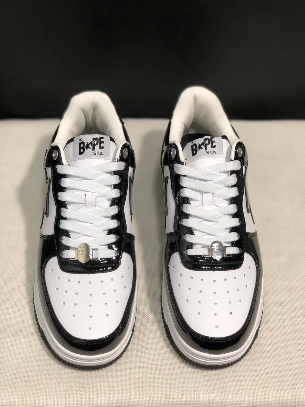 Front view highlighting the perforated white toe boxes, glossy black toe overlays and white laces.