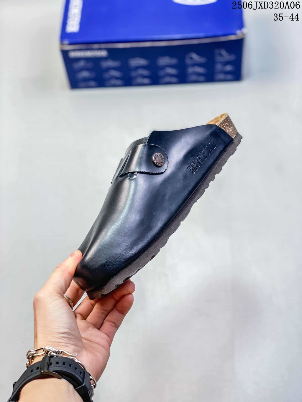 Side view of a black closed-toe clog showing the buckle strap, contoured upper, and textured sole.