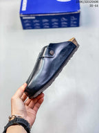 Side view of a black closed-toe clog showing the buckle strap, contoured upper, and textured sole.