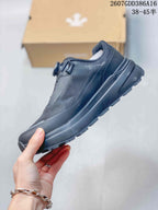 Side profile of the black low-top sneaker showing the streamlined upper, layered midsole, and treaded outsole.